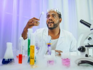 Scientist in white lab coat conducting colorful experiment with glassware and microscope.